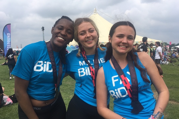 three fundraisers wearing BiD t shirts wearing medals after completing their race