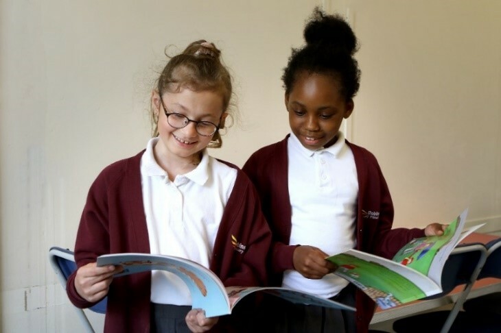 Two multi cultural children reading a book together