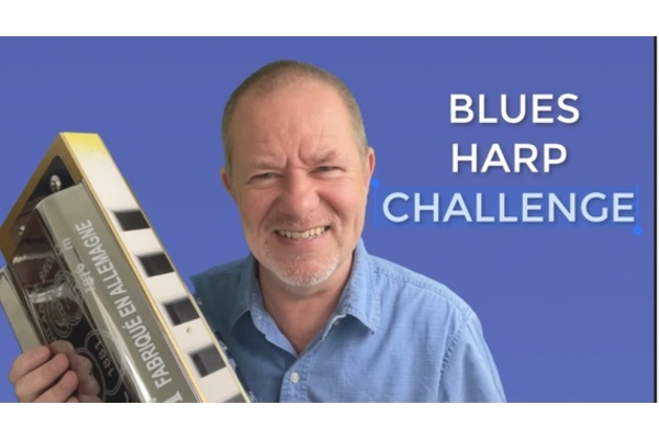 Photo of Ben Hewlett with massive 3ft Harmonica and words Blues harp challenge