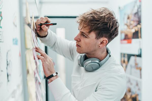 Young man writing on post it notes on a whiteboard