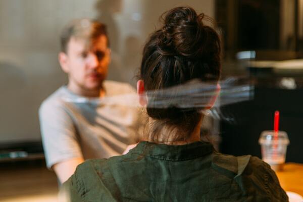 Looking through a window at the back of a woman's head, in conversation with a man opposite