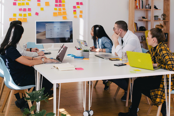 5 people around a desk looking at large screen